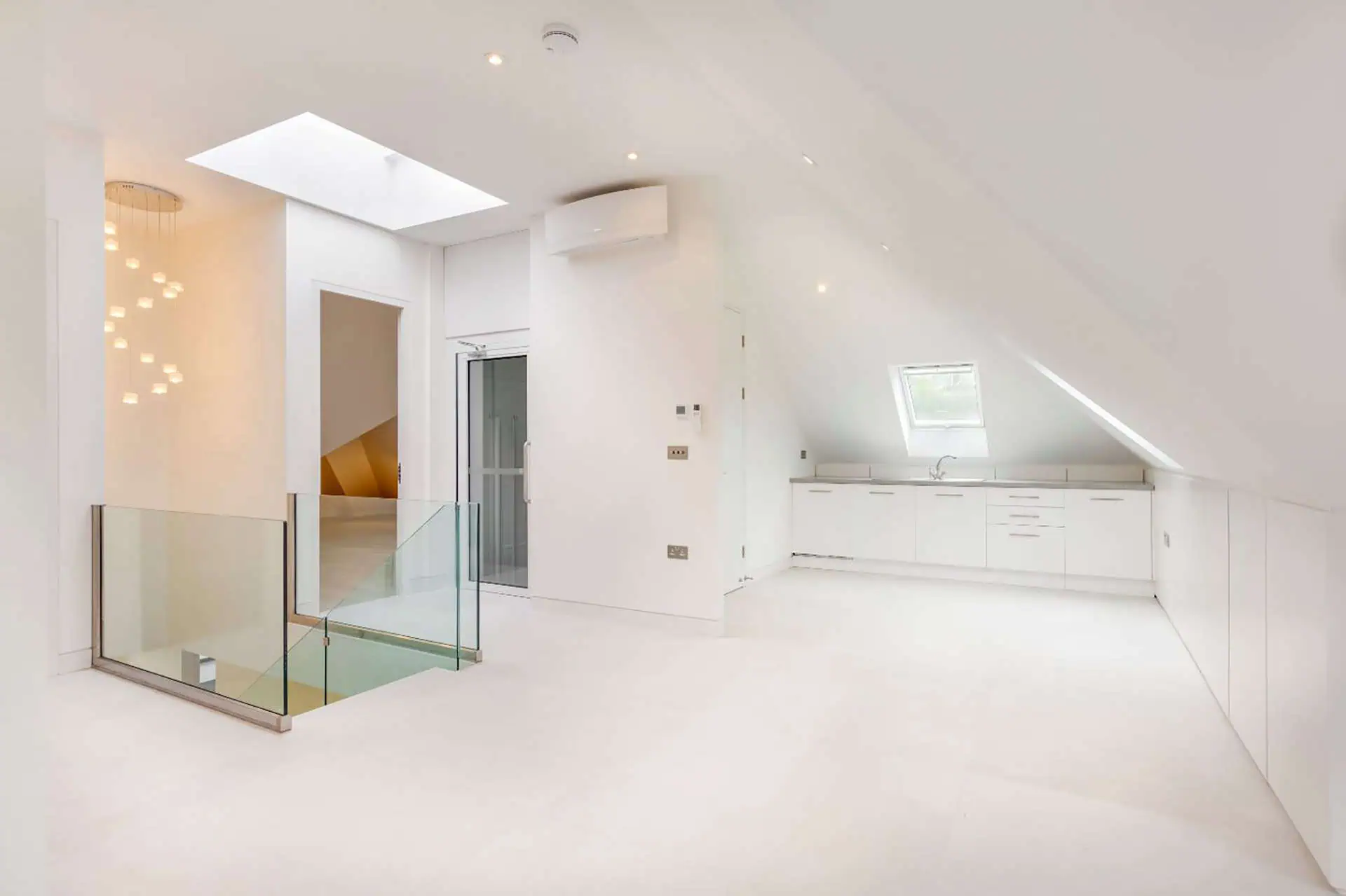 Luxury interior space featuring modern kitchen, glass railing, and skylight in Kensington new build project.