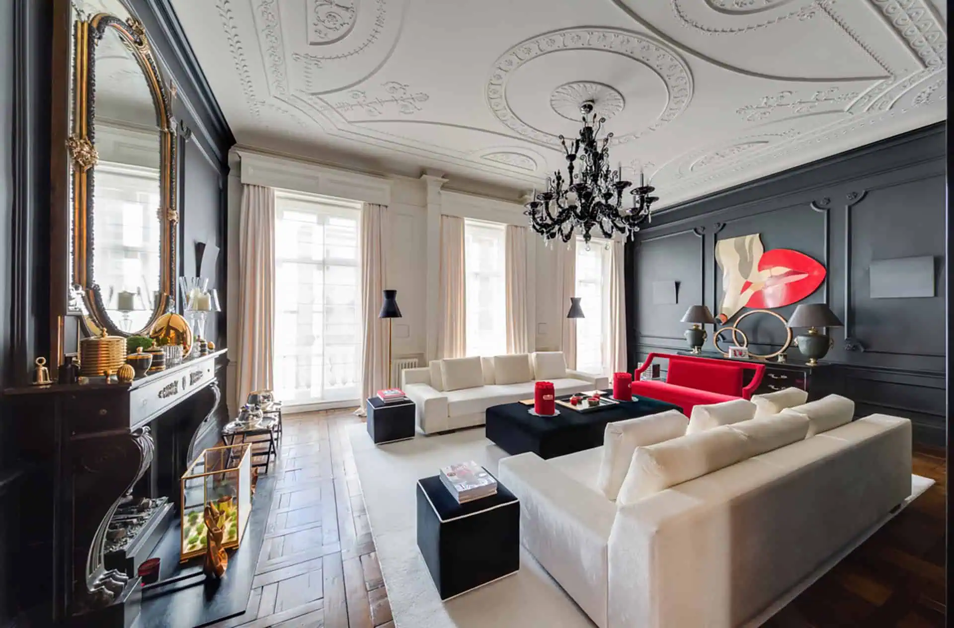 Luxury living room interior with elegant design, featuring white sofas, black coffee table, red accents, intricate ceiling details, and modern artwork, showcasing luxury home refurbishments in Belsize Park.